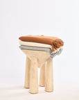 Wooden stool with three cushioned seats stacked on a white background