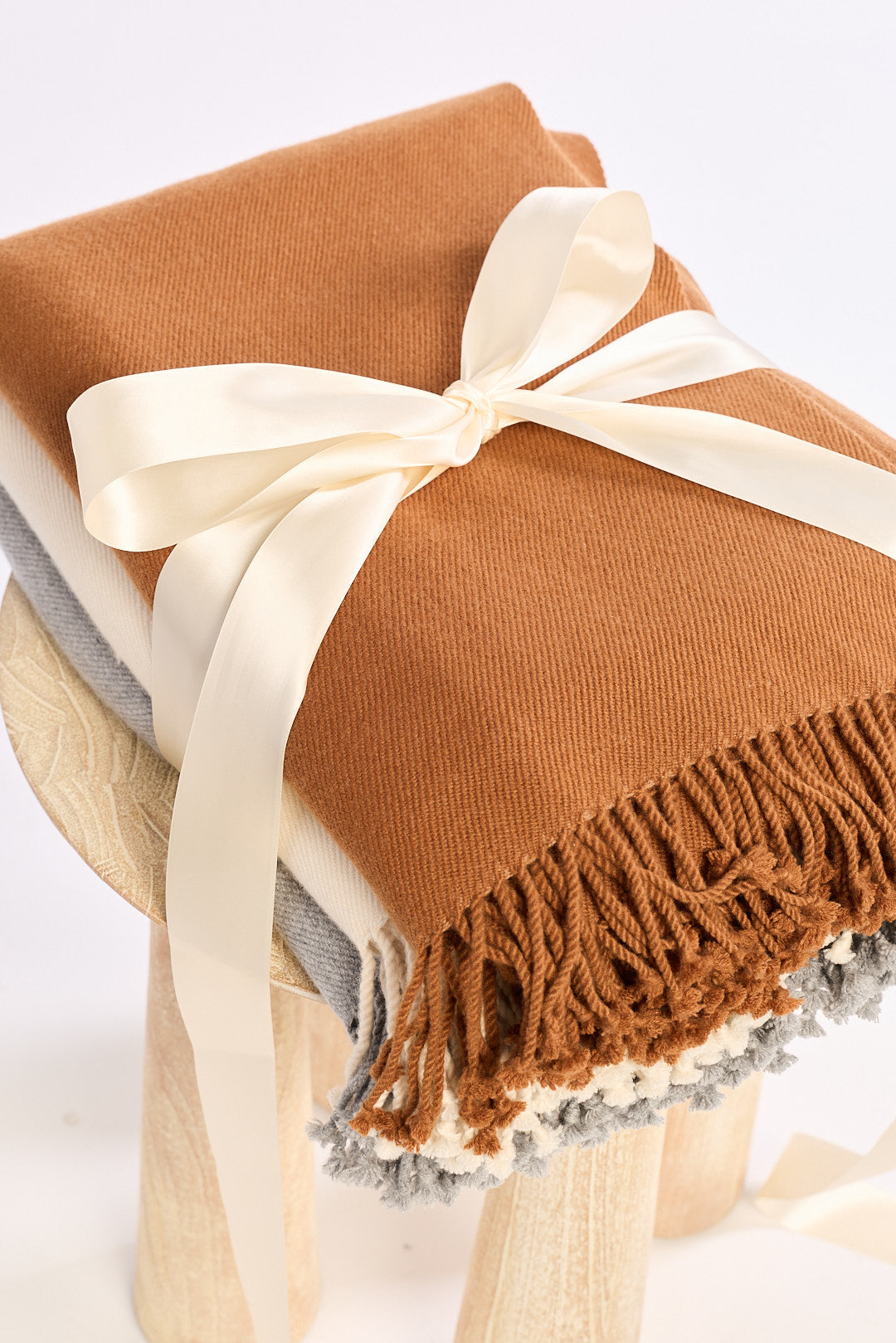 Brown blanket with fringes and a white bow on a white background