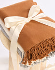 Brown blanket with fringes and a white bow on a white background