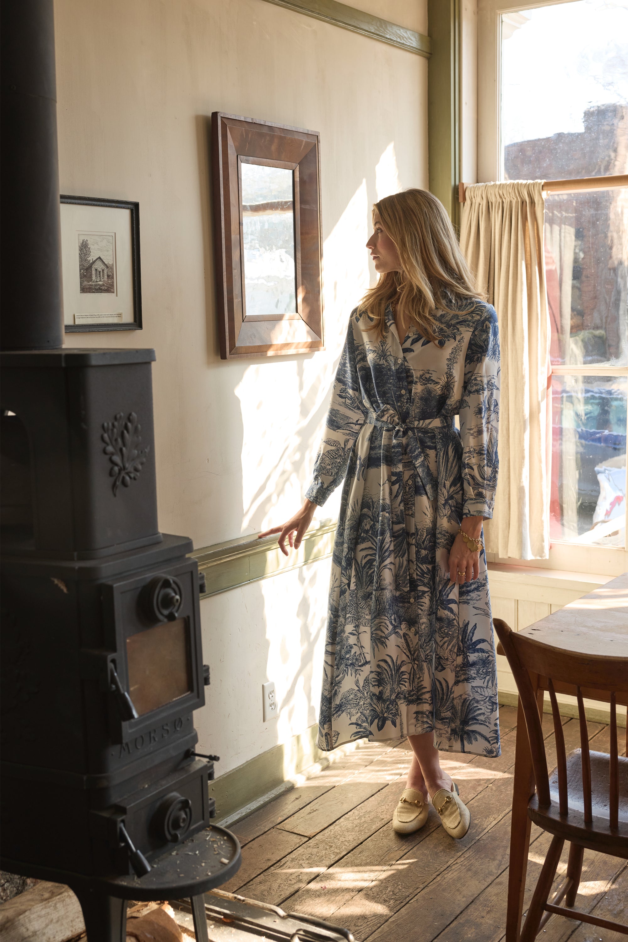 Woman modeling blue and white patterned dress in a home
