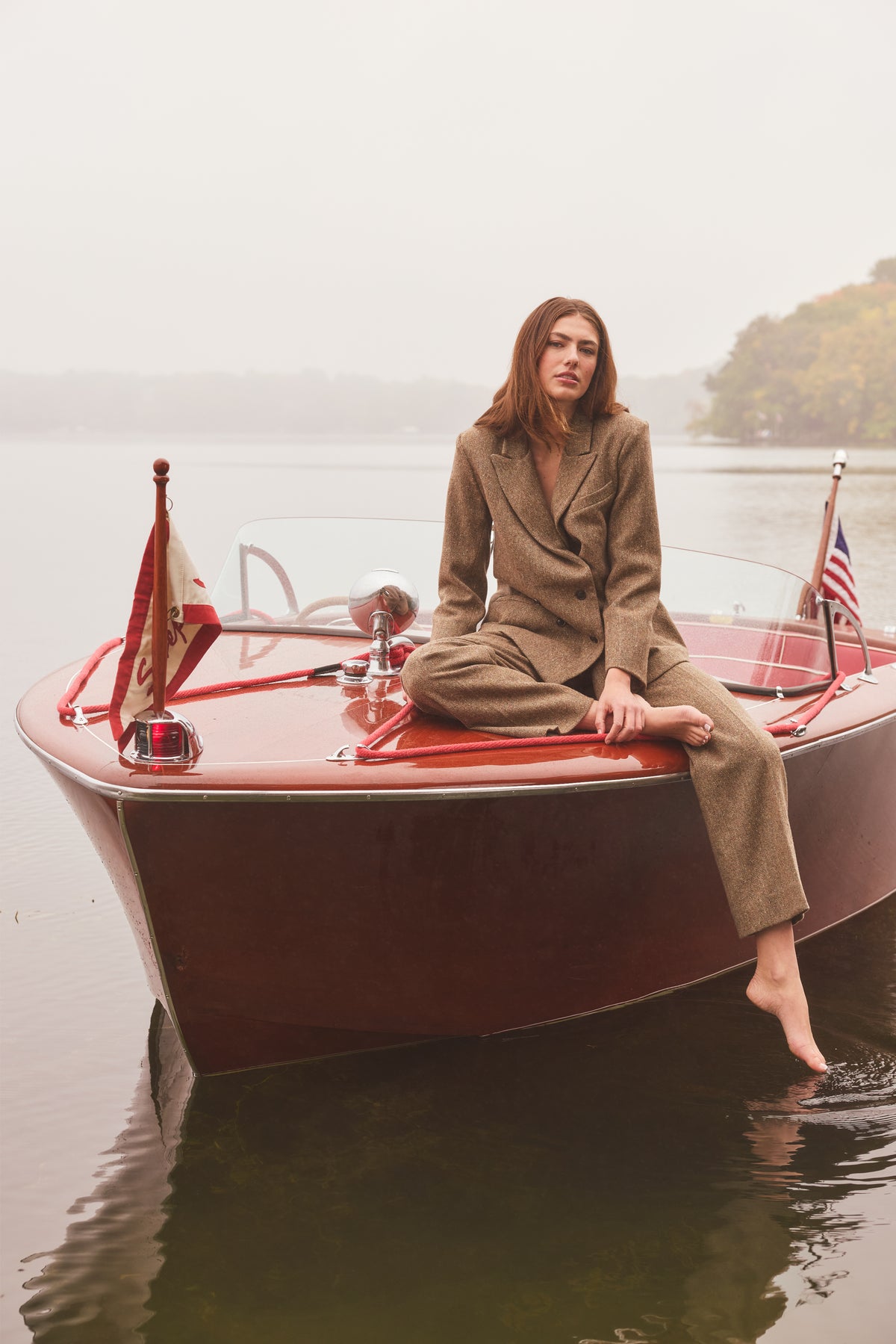 Woman sitting on a boat modeling a tweed blazer and pants