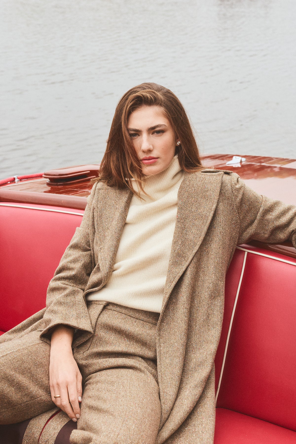 Woman modeling a long tweed coat sitting on a boat