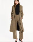 A woman modeling the Painter's Fleck Herringbone Anne Coat open over a black turtleneck and matching trousers, front view, photographed against a plain white studio background.