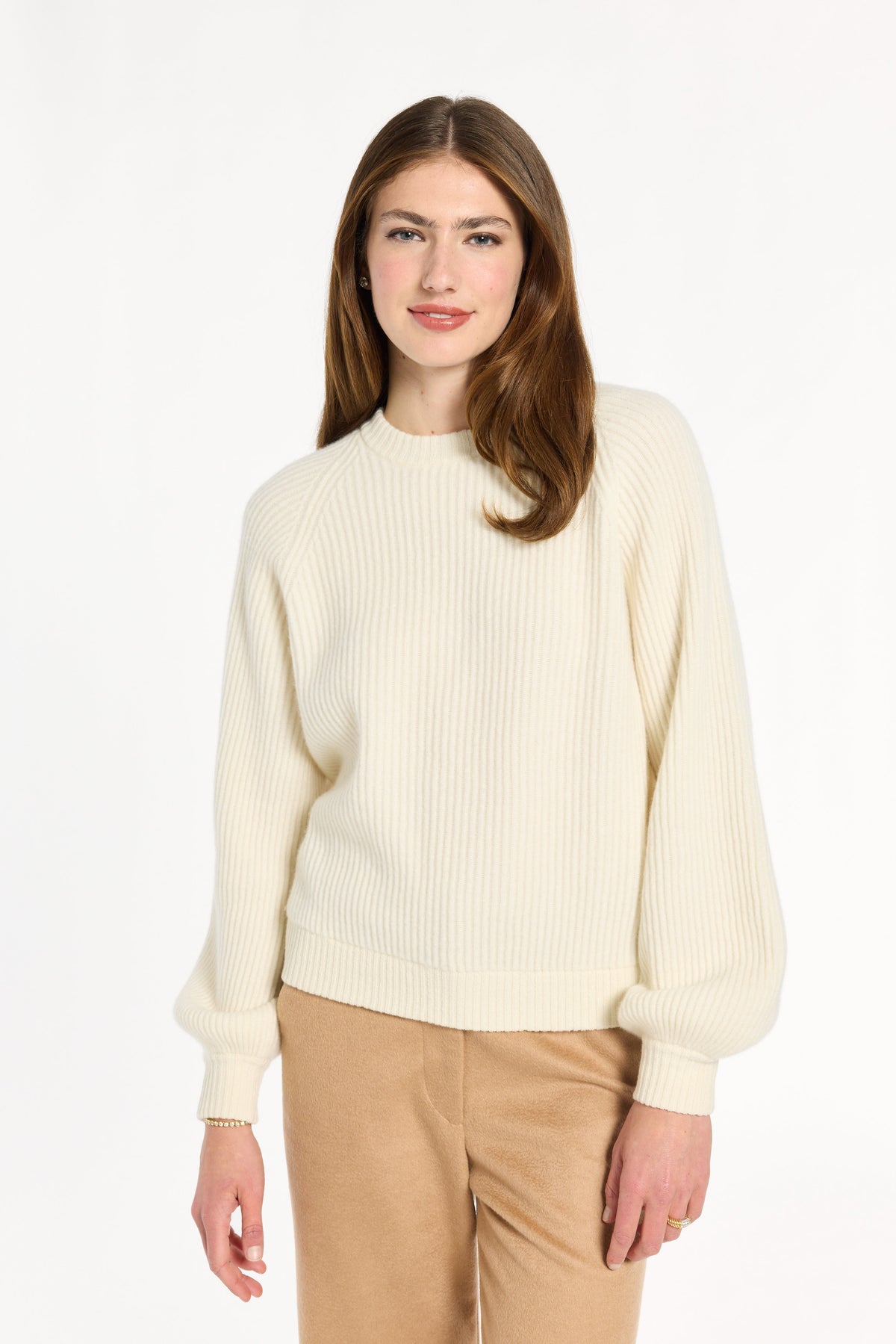 A woman modeling the cream Baby Cashmere Ribbed Crewneck with camel trousers, front view, photographed against a plain white studio background.