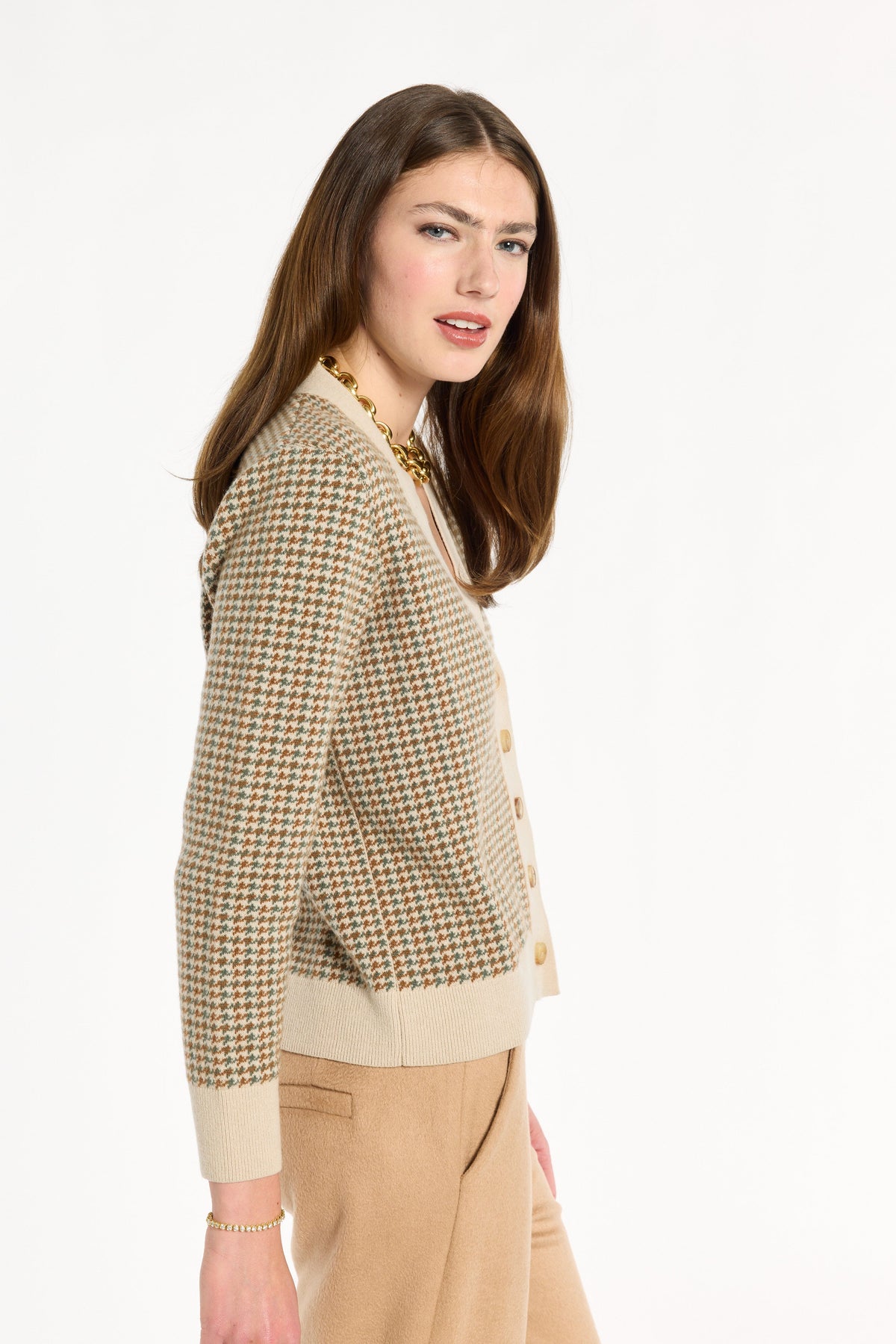 A woman modeling the Camel Tri-Color Check Classic Cashmere Cardigan with camel trousers, side view, photographed against a plain white studio background.