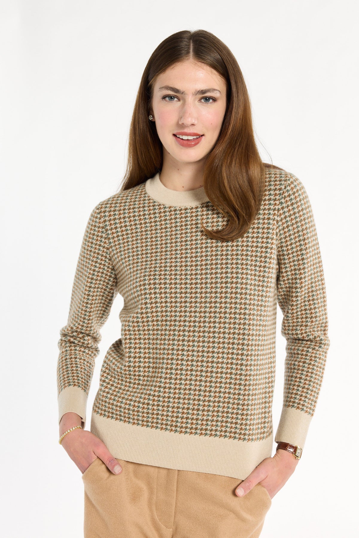 A woman modeling the Camel Tri-Color Check Classic Cashmere Crew with camel trousers, front view with hands in pockets, photographed against a plain white studio background.