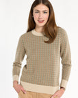 A woman modeling the Camel Tri-Color Check Classic Cashmere Crew with camel trousers, front view with hands in pockets, photographed against a plain white studio background.