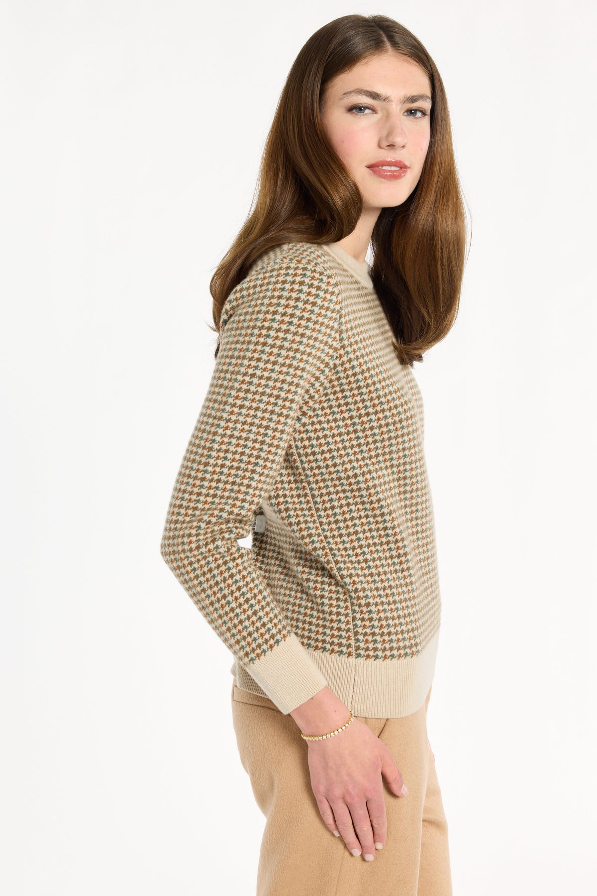 A woman modeling the Camel Tri-Color Check Classic Cashmere Crew with camel trousers, side view, photographed against a plain white studio background.
