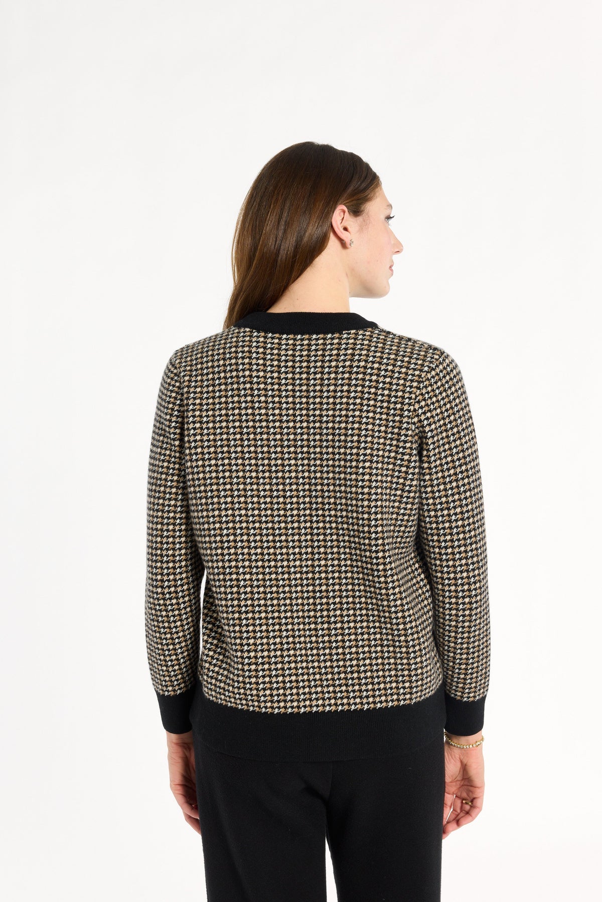 A woman modeling the Black Tri-Color Check Classic Cashmere Crew with black trousers, back view, photographed against a plain white studio background.