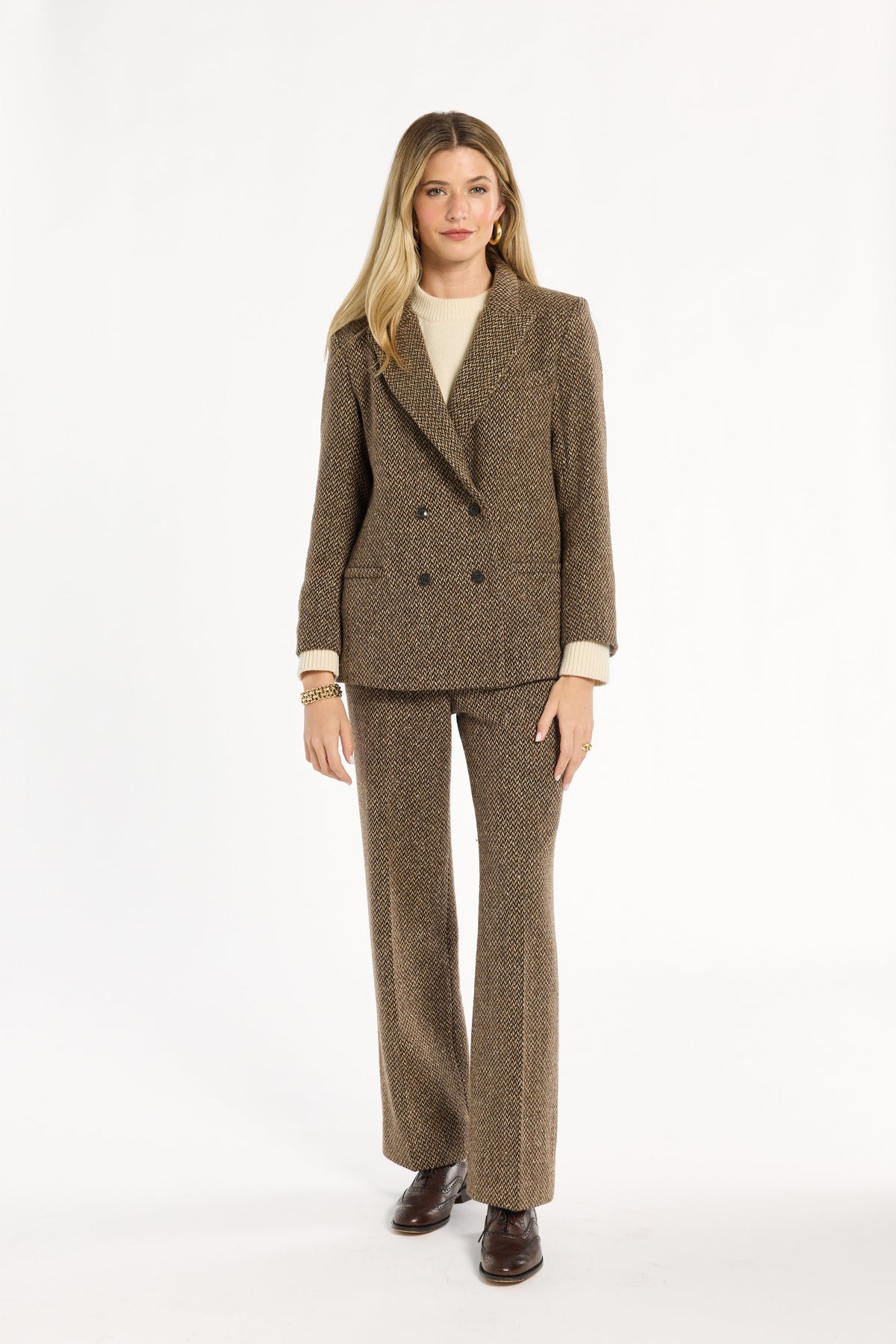 A woman modeling the double-breasted Tobacco Tweed Cynthia Blazer with a cream sweater and matching trousers, front view, photographed against a plain white studio background.