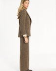 A woman modeling the Tobacco Tweed Cynthia Blazer with matching trousers, side view, photographed against a plain white studio background.