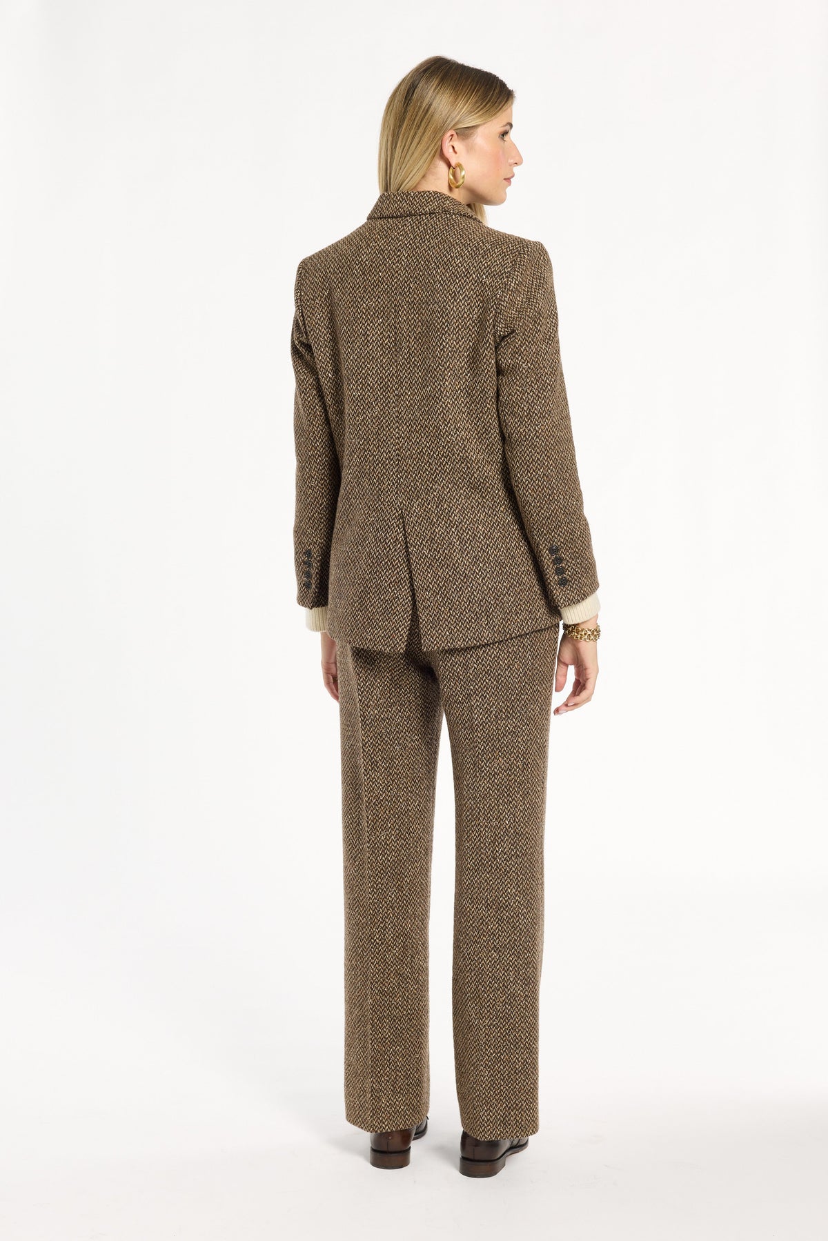 A woman modeling the Tobacco Tweed Cynthia Blazer with matching trousers, back view, photographed against a plain white studio background.