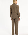A woman modeling the Tobacco Tweed Cynthia Blazer with matching trousers, back view, photographed against a plain white studio background.