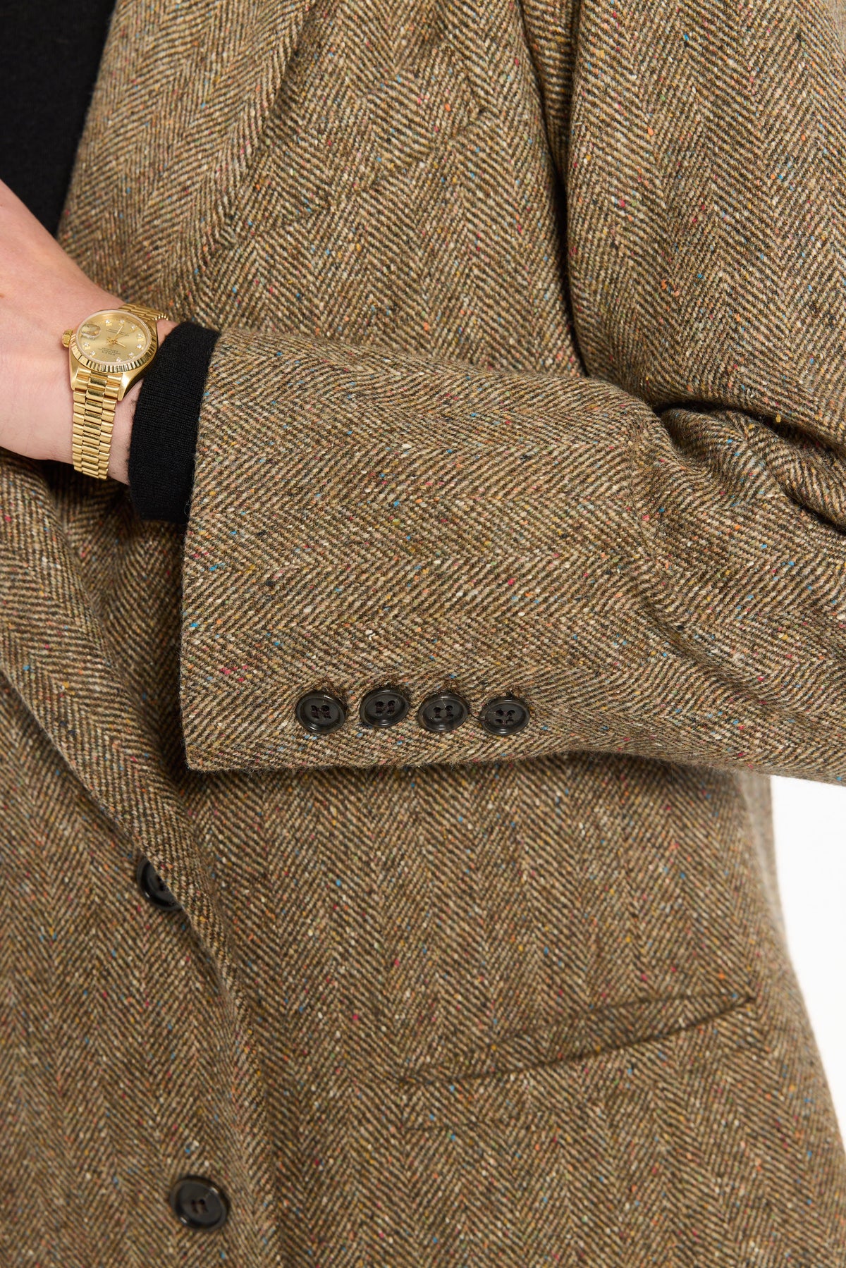 Close-up of the buttoned cuff, pocket, and flecked herringbone texture of the Cynthia Blazer, photographed against a plain white studio background.