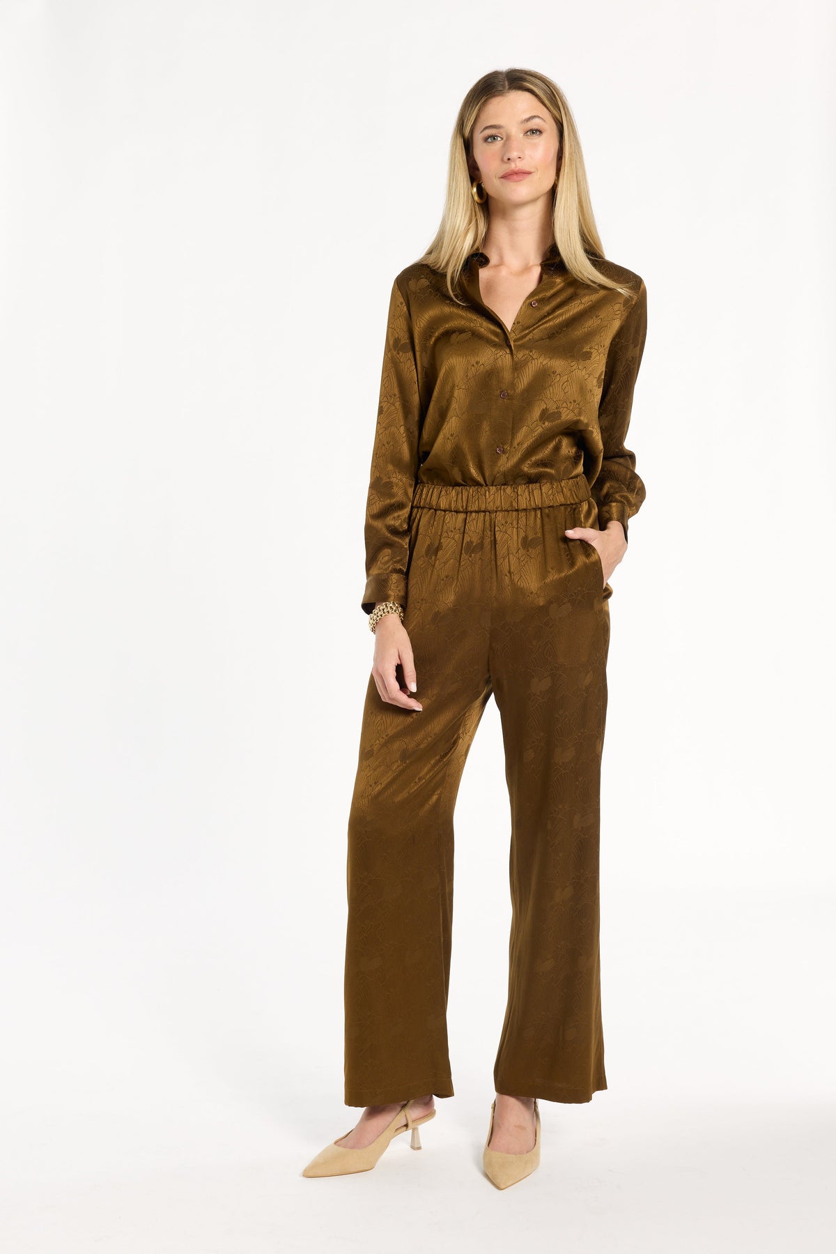 A woman modeling the Golden Umber Diane Pants with the coordinating Eleanor Shirt and cream heels, full-length front view, photographed against a plain white studio background.