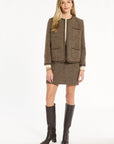 A woman modeling the Tobacco Tweed Dusti Jacket with the matching Meg Mini Skirt and dark brown knee-high boots, front view, photographed against a plain white studio background.