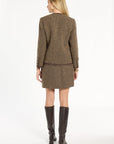 A woman modeling the Tobacco Tweed Dusti Jacket with the matching mini skirt and knee-high boots, back view, photographed against a plain white studio background.