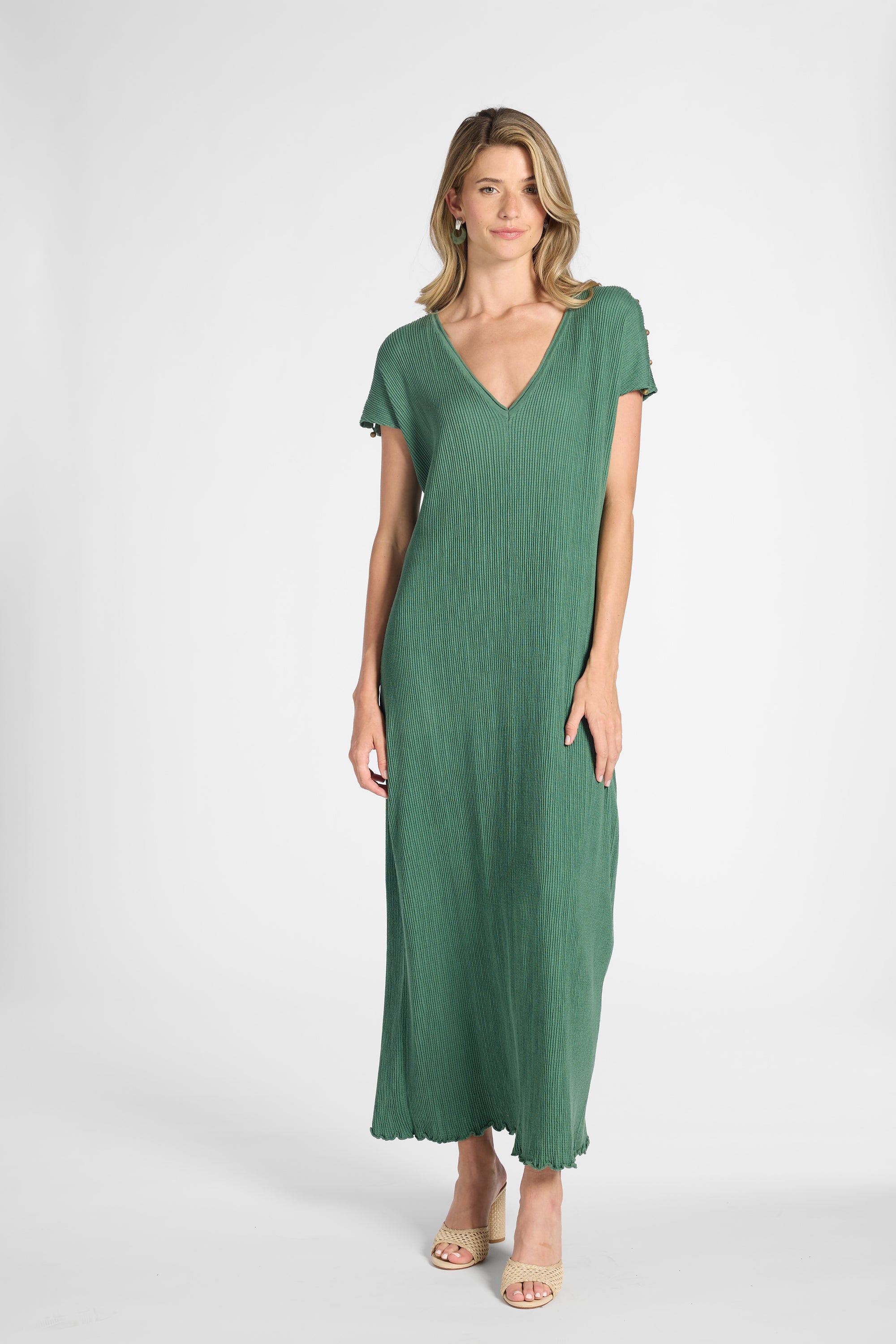 A woman modeling a green short-sleeve dress with a V-neckline and subtle crinkle texture, standing against a gray background.
