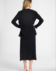 A woman shown from the back wearing a black long-sleeve cardigan and matching midi skirt set on a white backdrop