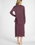 Woman modeling a silk pleated purple cardigan and the matching skirt on a white backdrop
