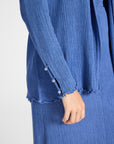 Close up image of a pleated blue cardigan with gemstone buttons on the sleeve