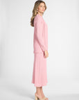 Woman modeling a silk pink cardigan and the matching skirt with nude heels on a white backdrop