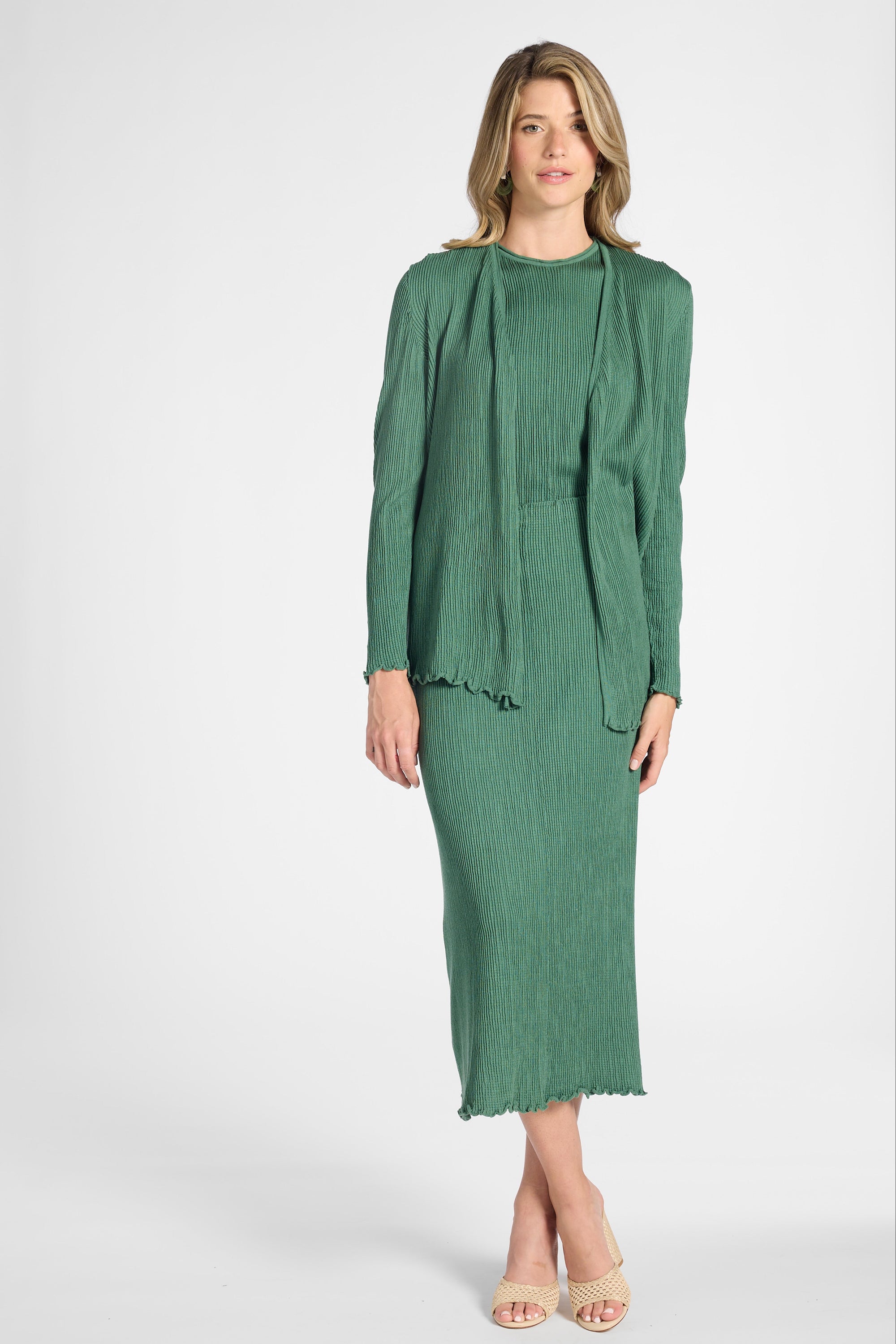 Woman modeling a sage green cardigan with buttons on sleeve on a white backdrop