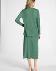 Woman modeling a pleated green cardigan with gemstones with the matching pleated skirt on a white background