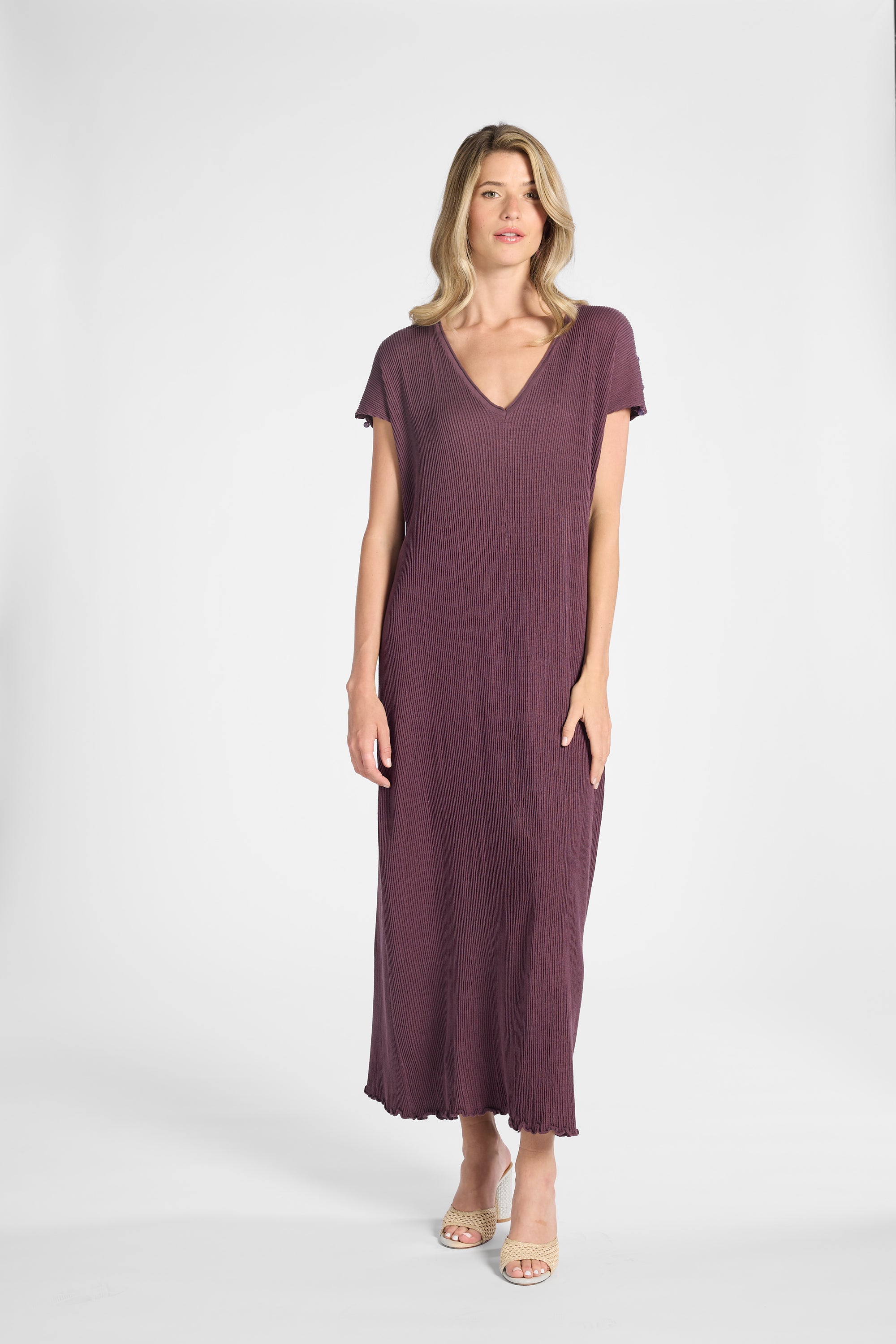 A woman modeling a purple pleated dress on a white background