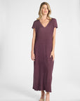 A woman modeling a purple pleated dress on a white background