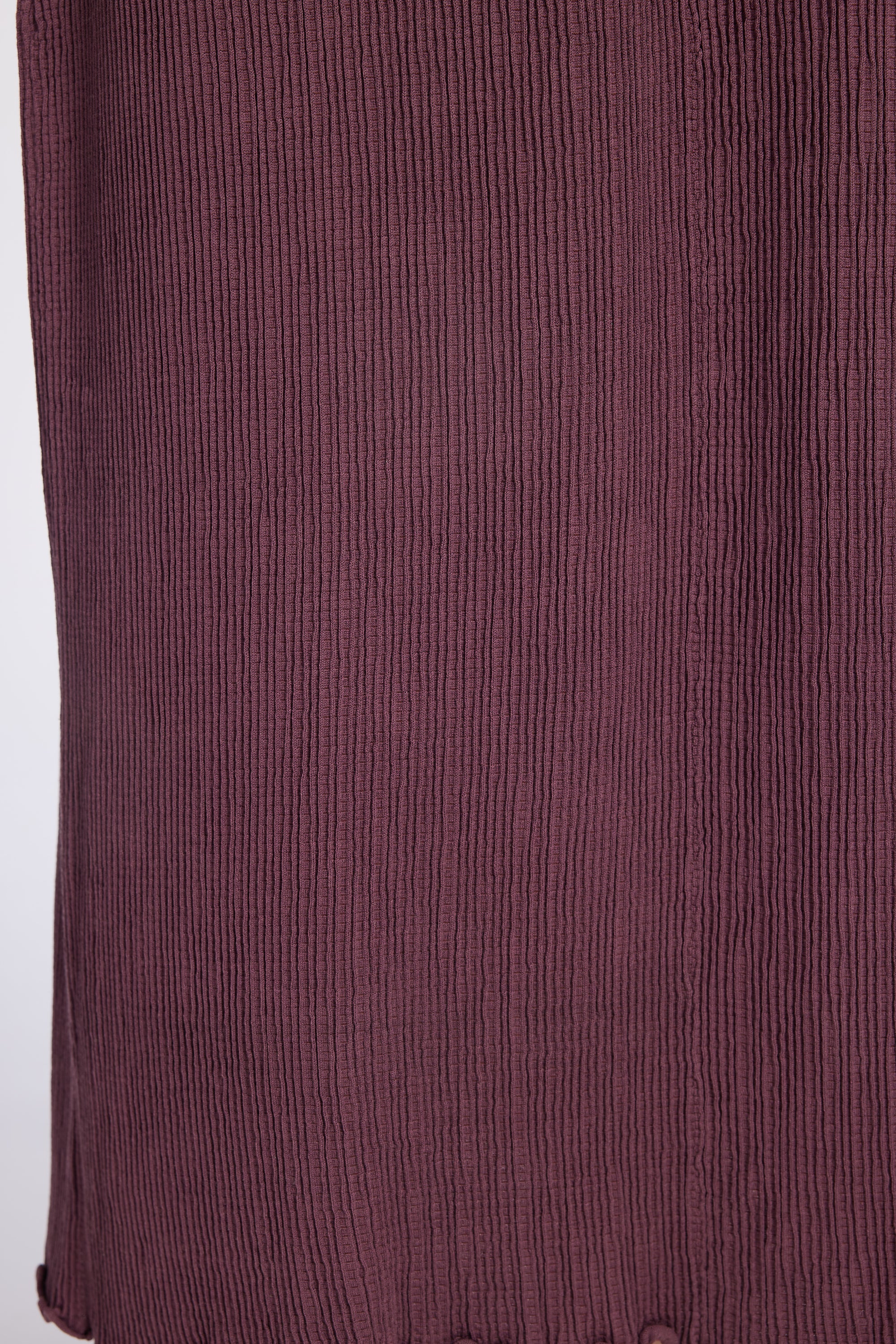 Close-up of a textured, vertically pleated fabric in purple color.