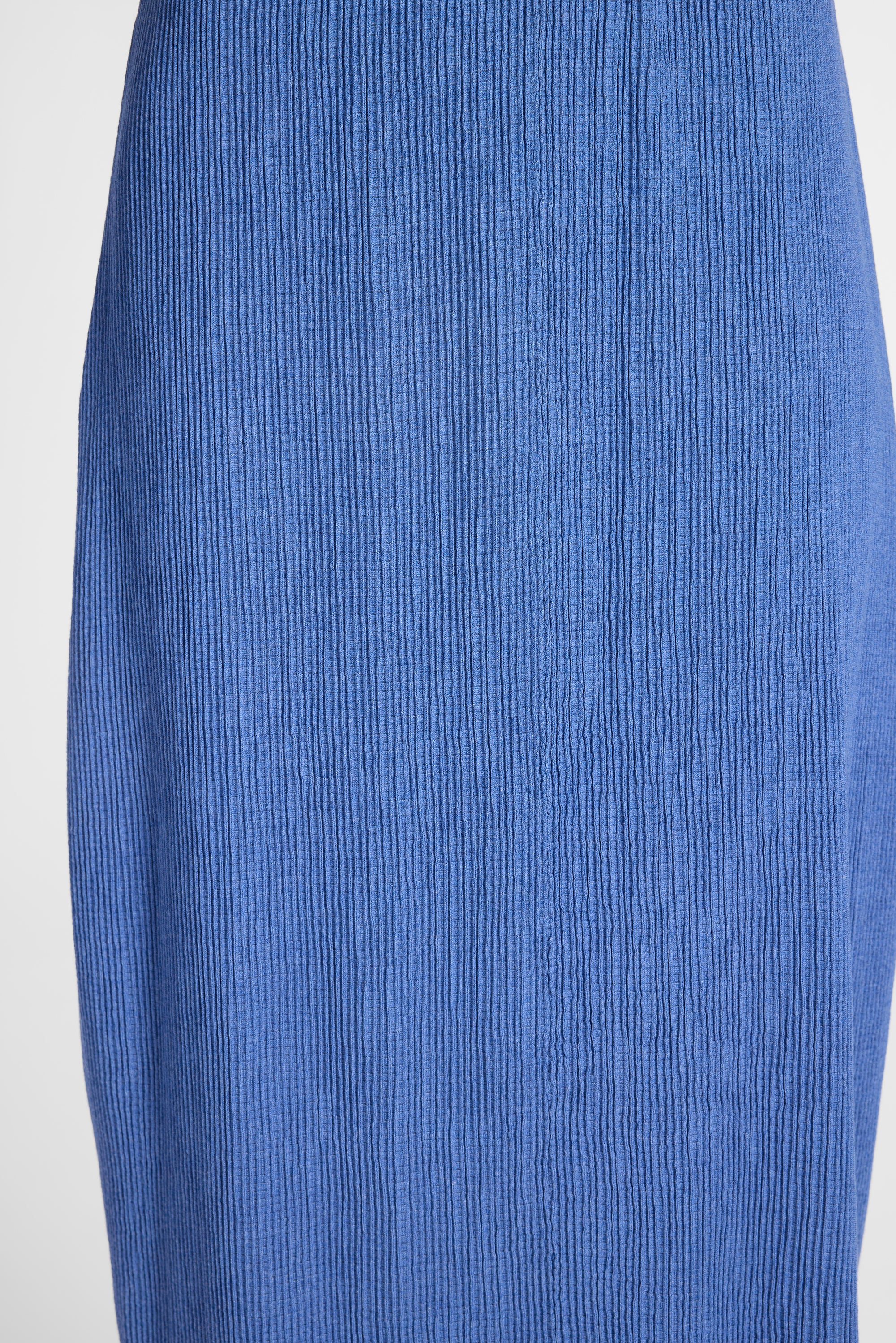A close-up of a blue vertically ribbed or pleated fabric texture, showing the material detail and color.