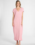 A woman modeling a light pink short-sleeve maxi dress with a V-neckline, photographed against a plain light gray studio background.