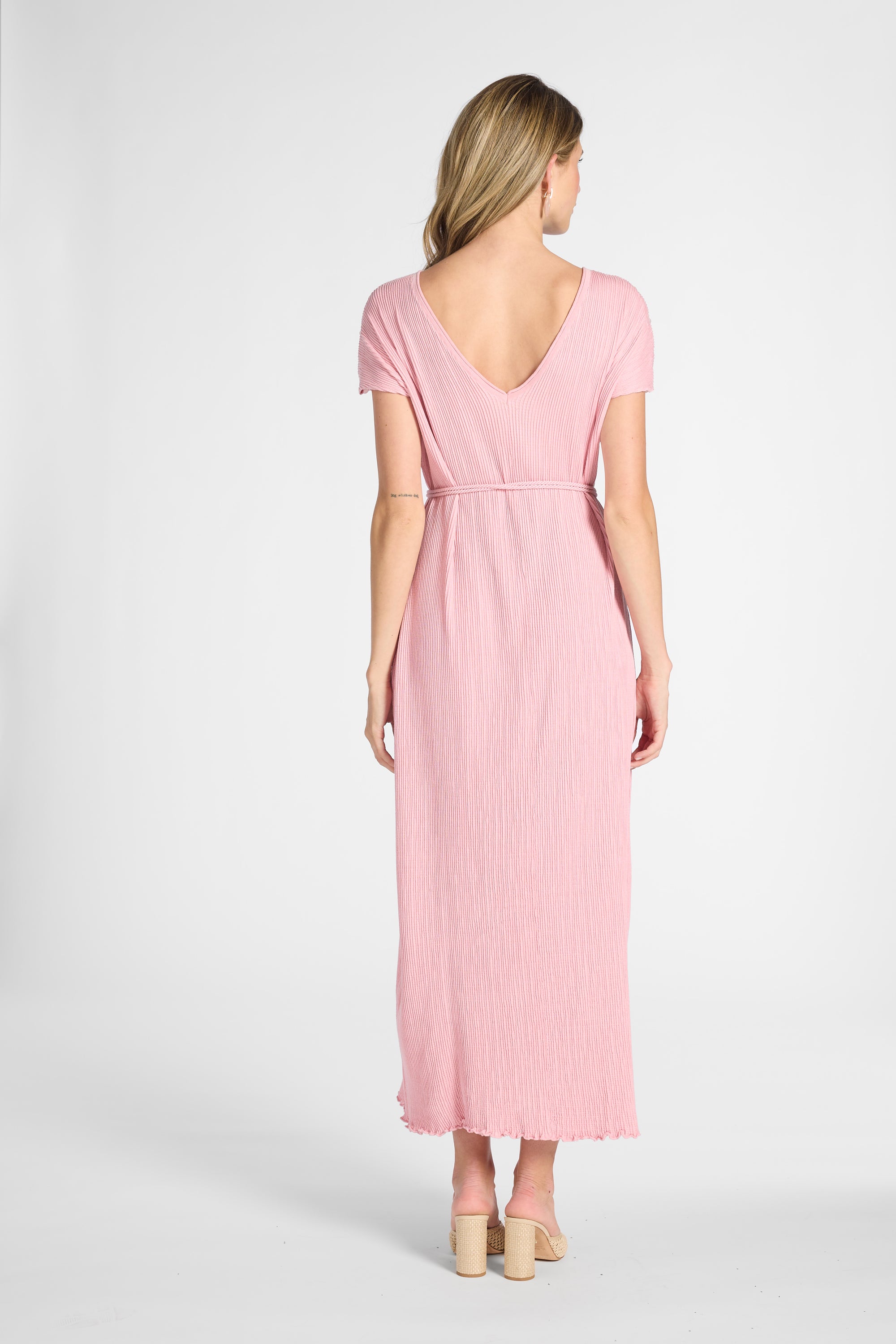 A woman modeling a silk pleated dress on a white backdrop