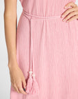 Close-up of a pink ribbed dress with a matching braided tie belt and tassel, worn by a model against a light gray background.