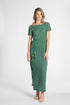 A woman modeling a green short-sleeve maxi dress with decorative tassel details on the waist and sleeve edges, photographed against a plain light gray studio background.