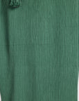 Close-up of a green pleated fabric with a small tassel detail at the top left.