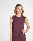Woman modeling a pleated purple shell on a white backdrop