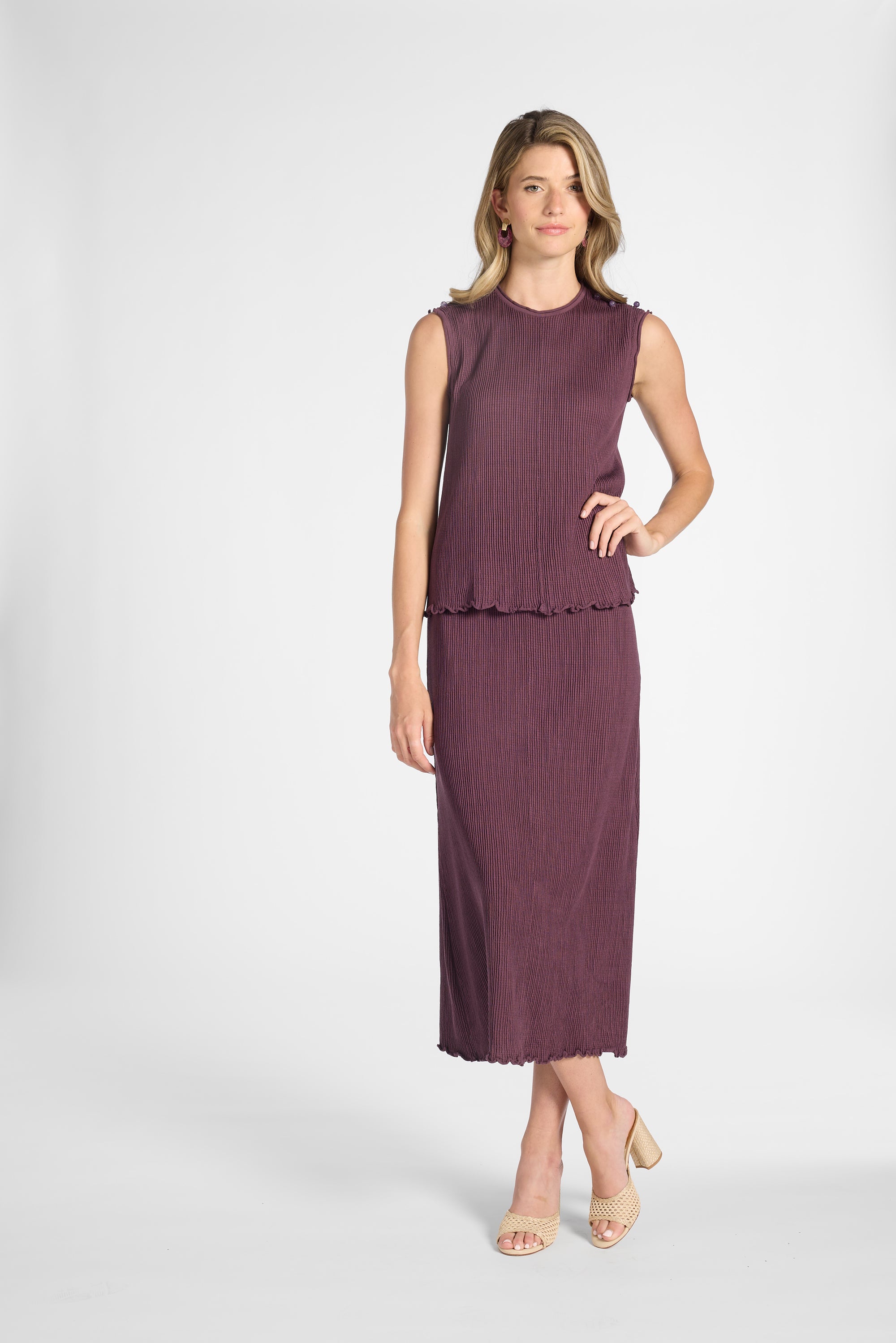 Woman modeling a purple pleated shell and the matching skirt on a white backdrop