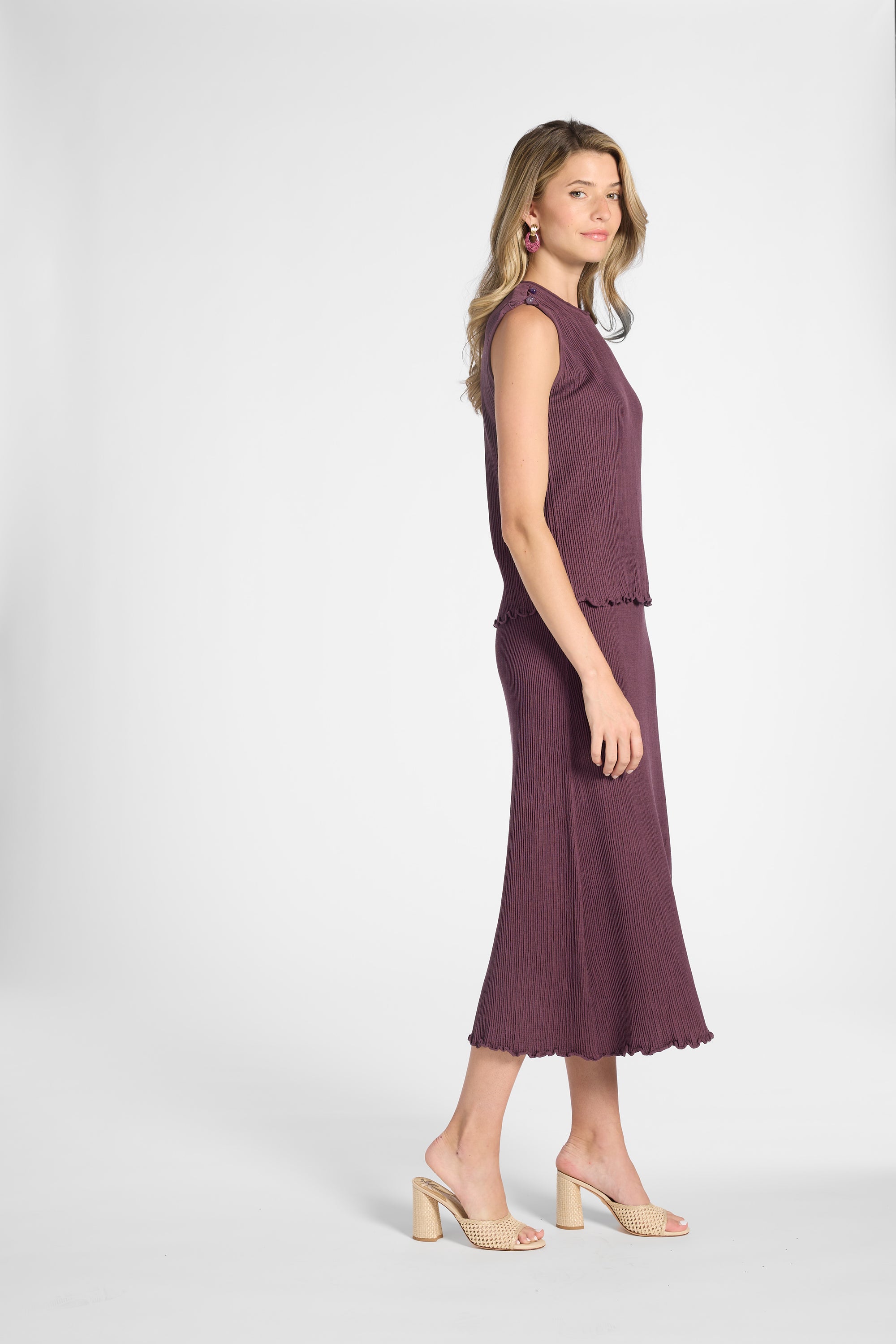 Woman modeling a purple pleated skirt and the matching shell on a white backdrop