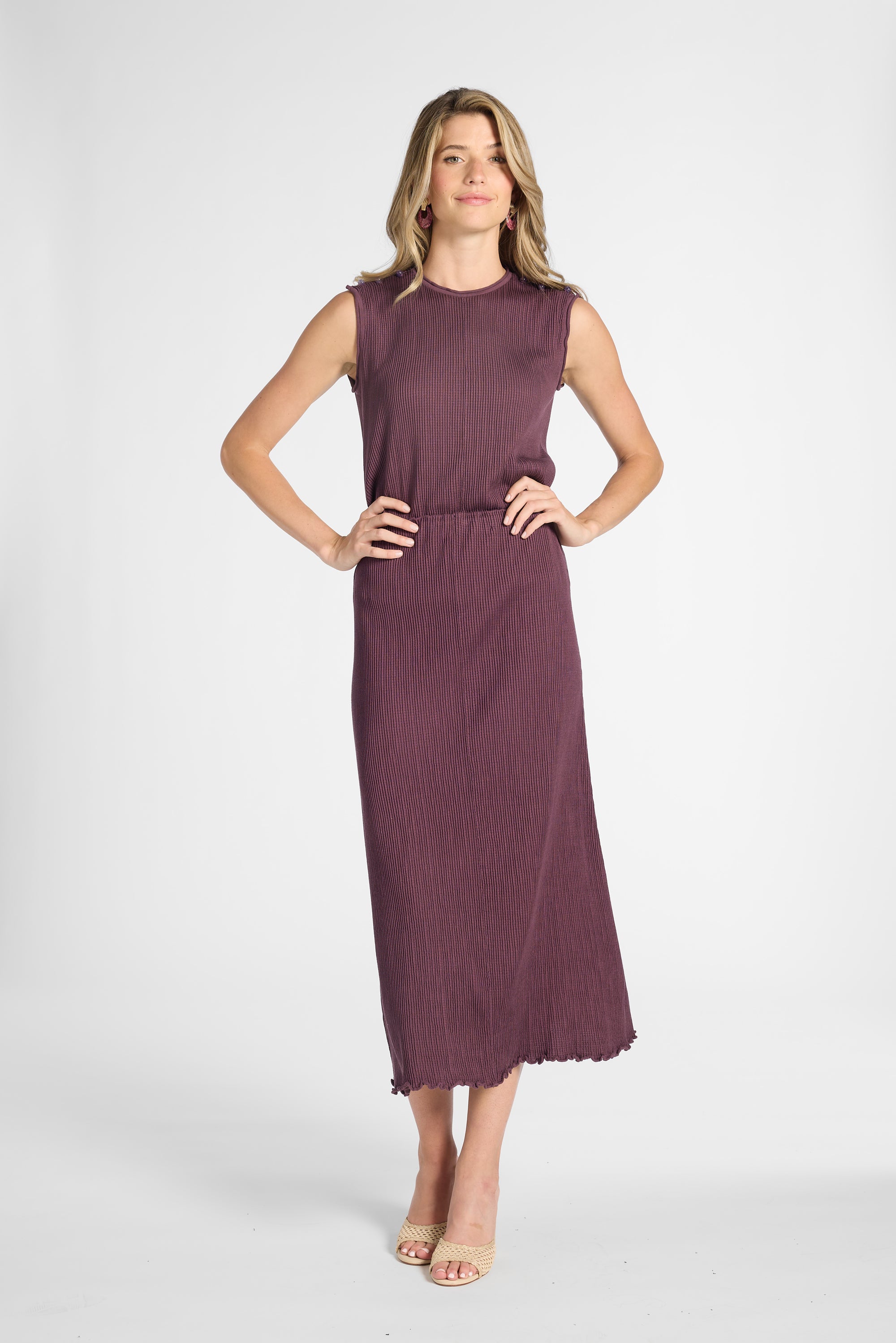 Woman modeling a purple pleated shell top with the matching skirt on a white backdrop