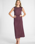 Woman modeling a purple pleated shell top with the matching skirt on a white backdrop