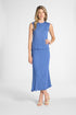 Woman modeling a pleated silk shell with the matching blue skirt on a white backdrop