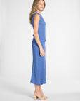 A woman standing to the side modeling a pleated blue outfit
