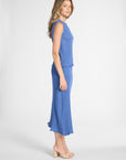 A woman modeling a sleeveless blue shell and skirt with a textured, shown in profile against a light gray studio background