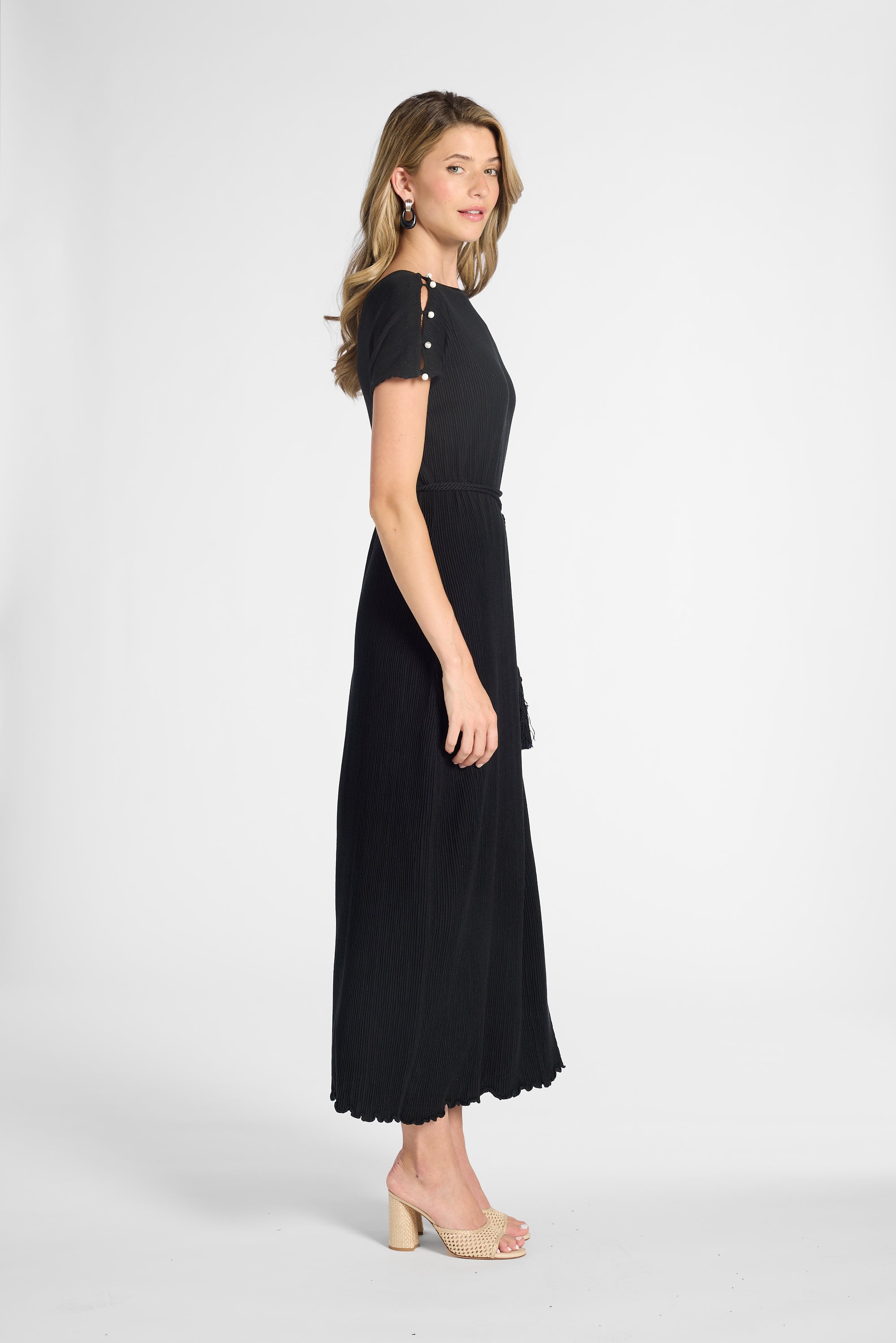 A woman modeling a pleated black dress on a white background