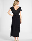 A woman wearing a pleated onyx dress on a white background with nude heels