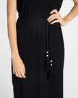 Close up of a black silk pleated dress on a white backdrop