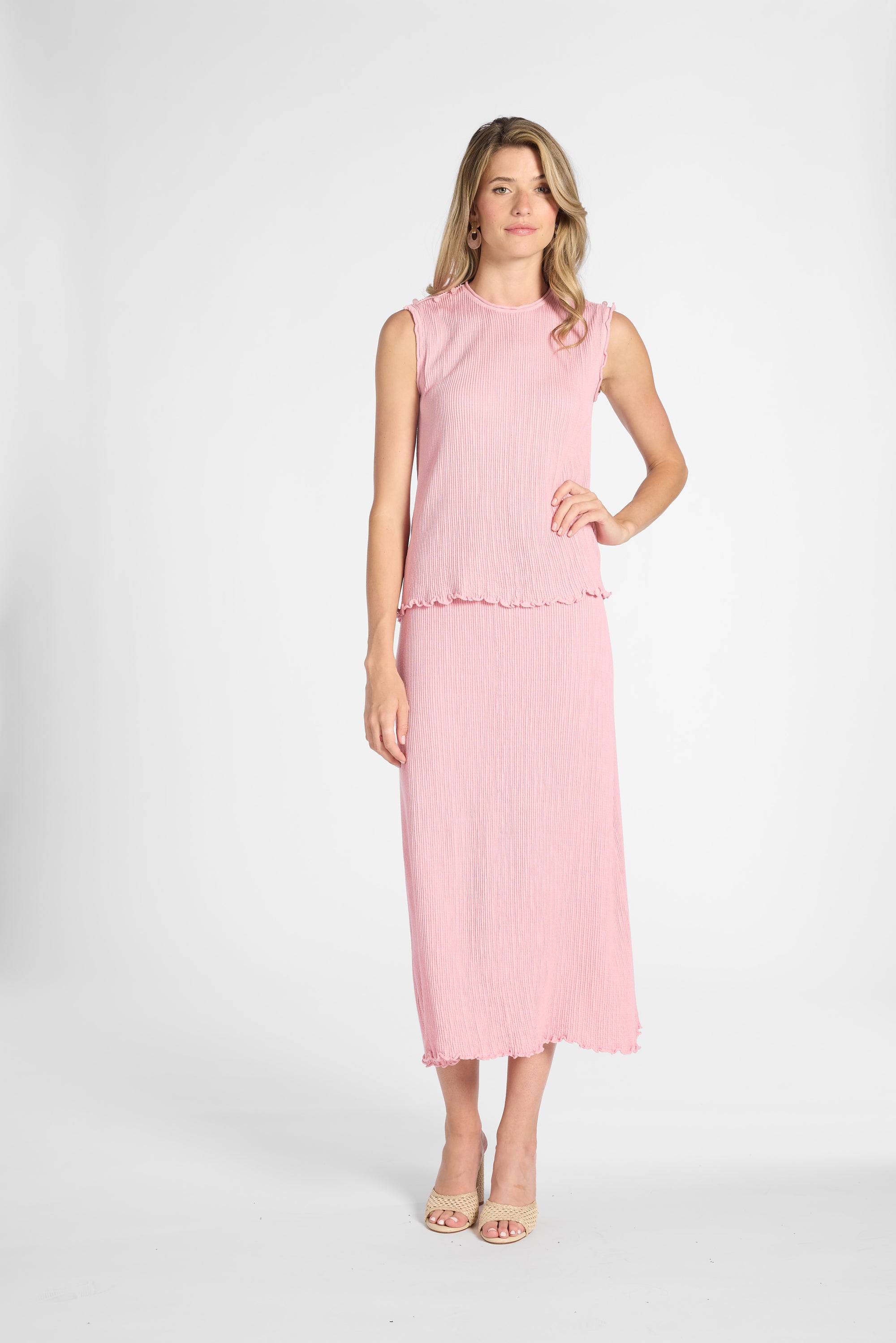 Woman modeling a pleated silk blouse and the matching skirt on a white backdrop