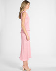 A woman modeling a pleated pink blouse with a matching pink pleated skirt